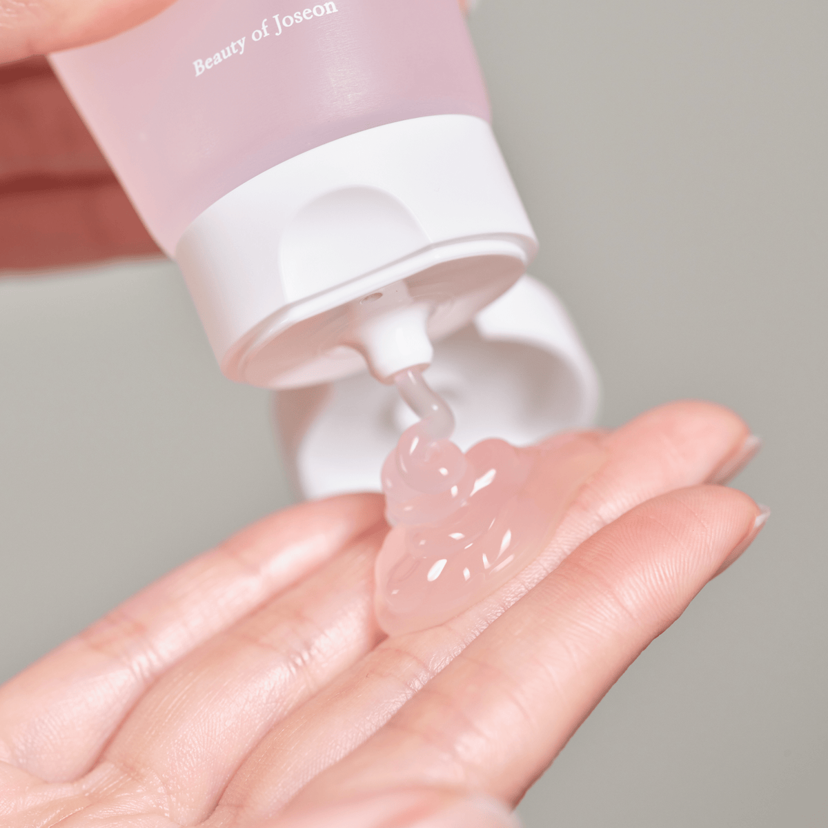 a hand with a pink bottle of liquid
