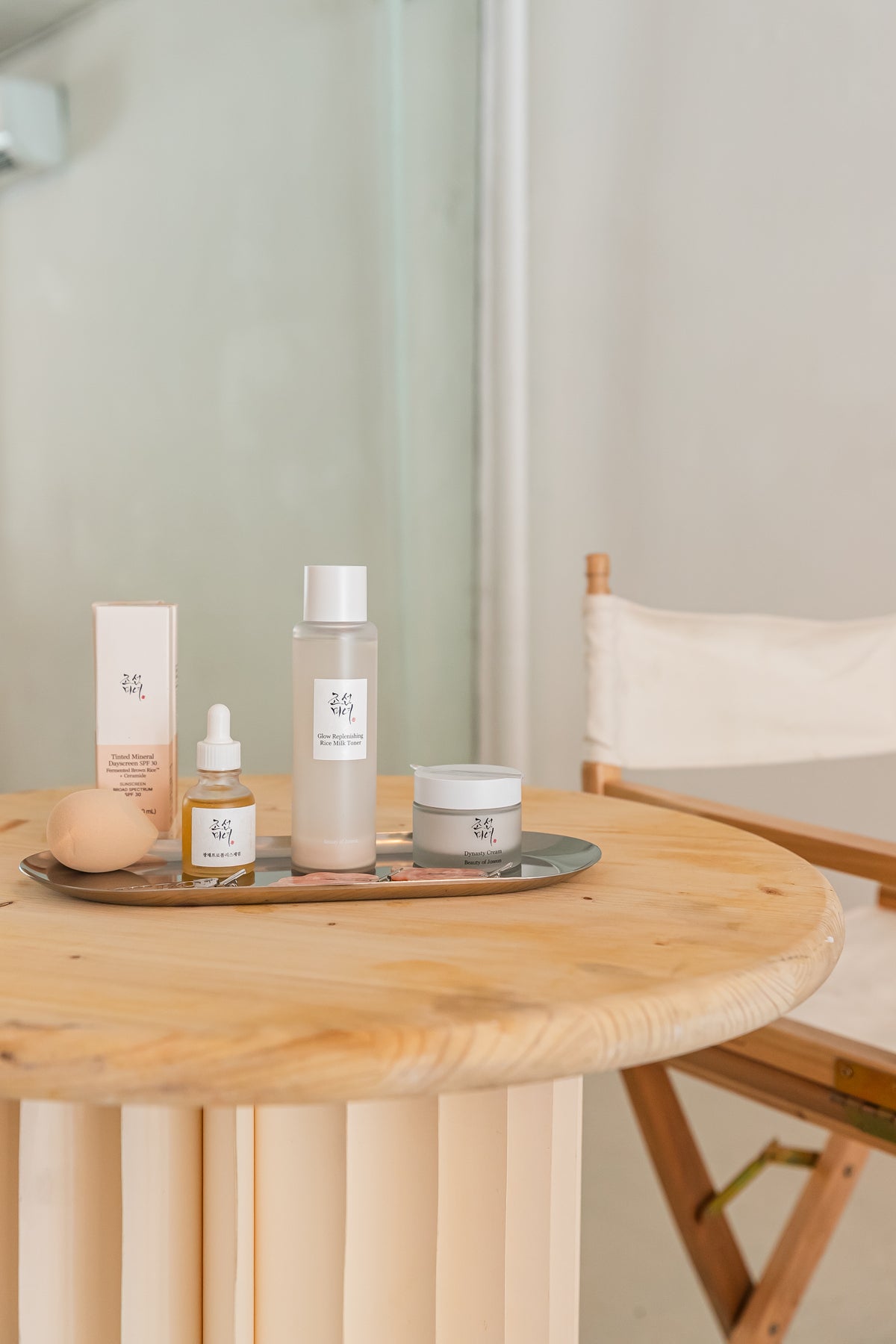 Glow Serum, Dynasty Cream, and other products are arranged on a wooden table.
